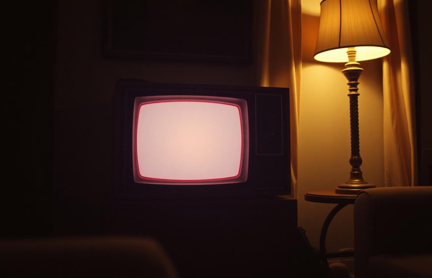 Televisore in legno degli anni Settanta acceso in un salotto in penombra