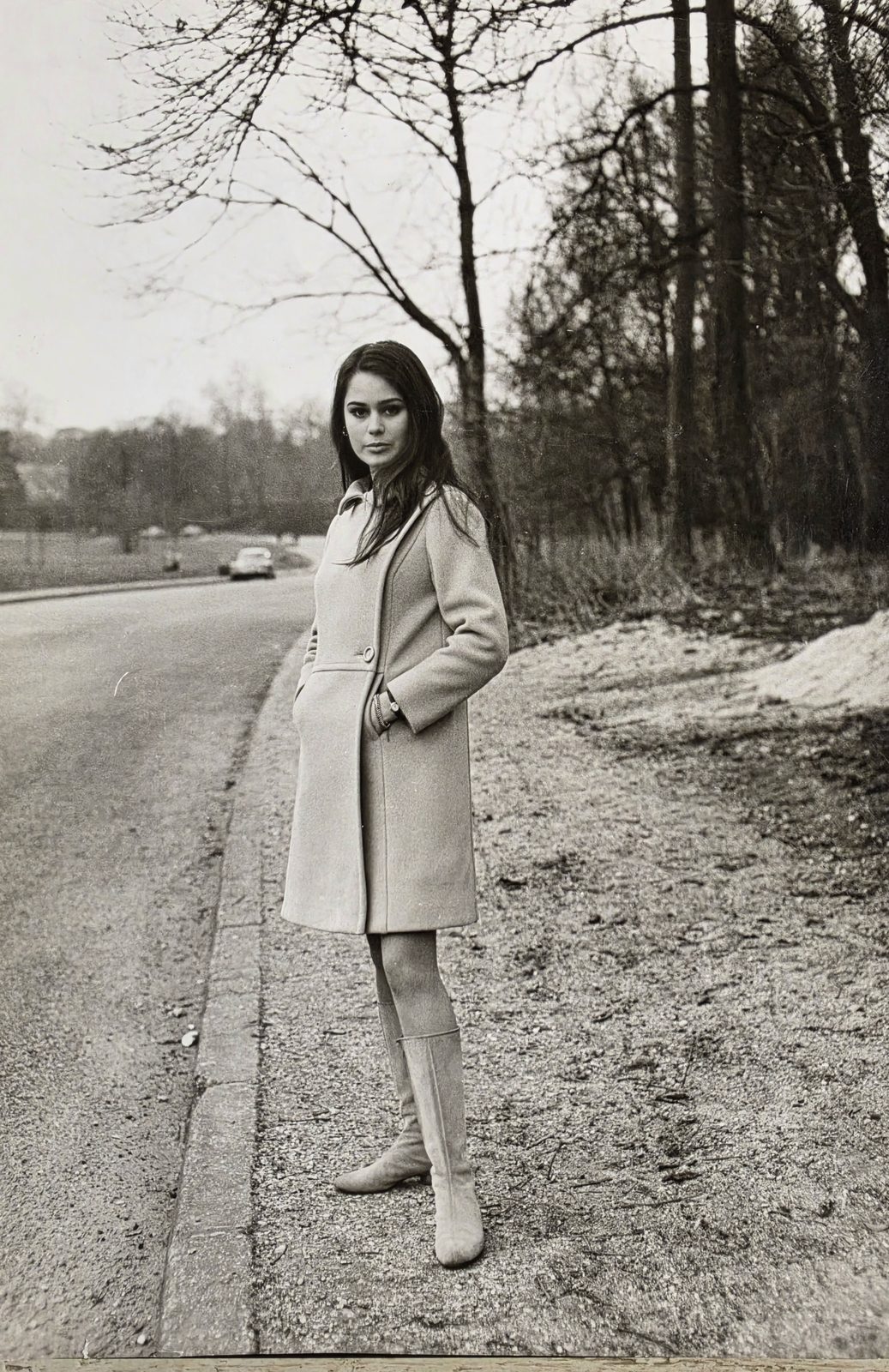Corinne Cléry giovanissima per le strade di Parigi, cappotto e sguardo verso l'obiettivo